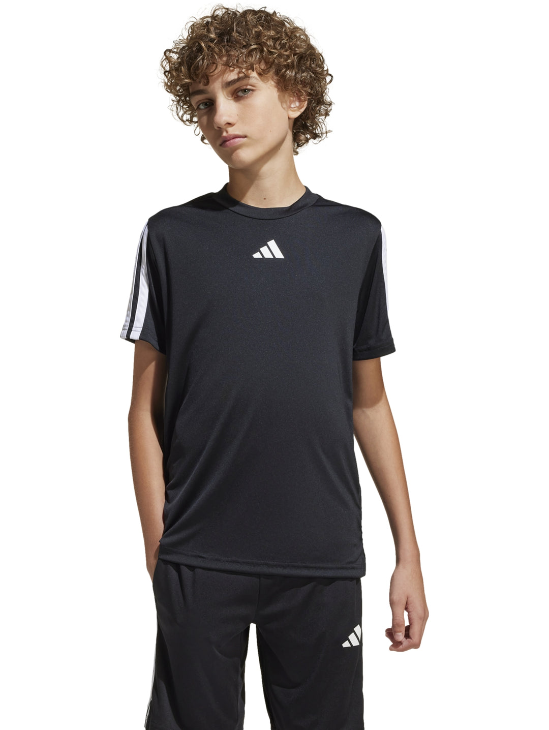 Niño vistiendo camiseta deportiva Adidas color negro con tres franjas blancas en los hombros.
