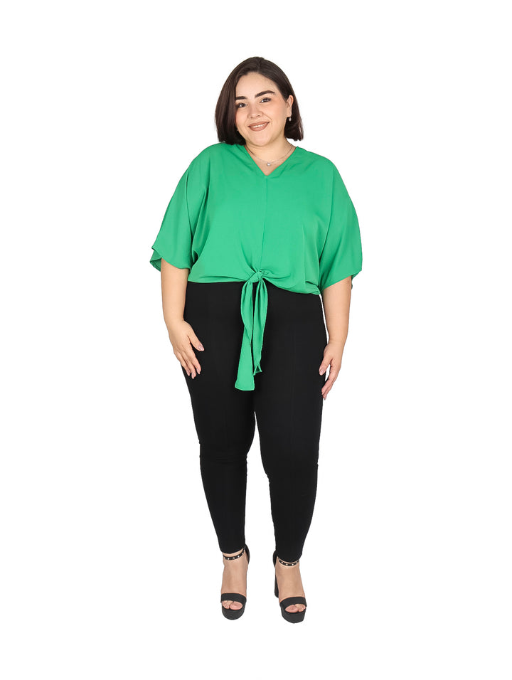 Mujer vistiendo una blusa color verde kelly con amarre frontal y pantalones negros.