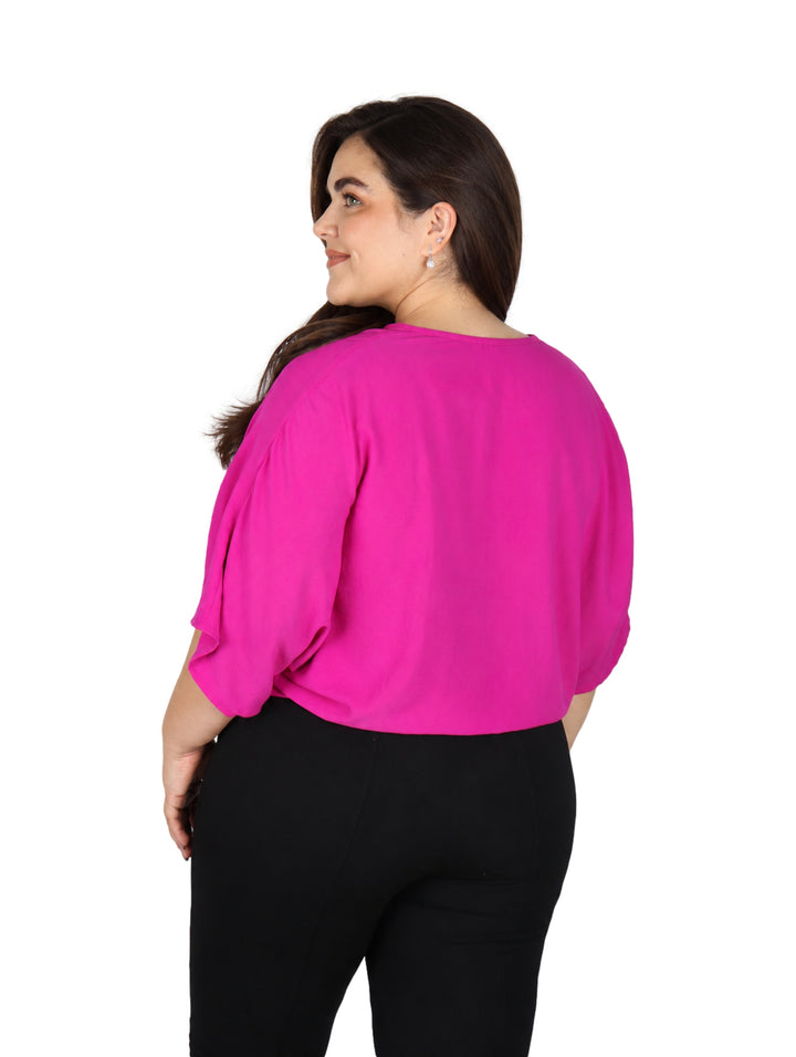 Mujer vistiendo una blusa color rosa intenso con cuello en V y detalle de nudo en la cintura.