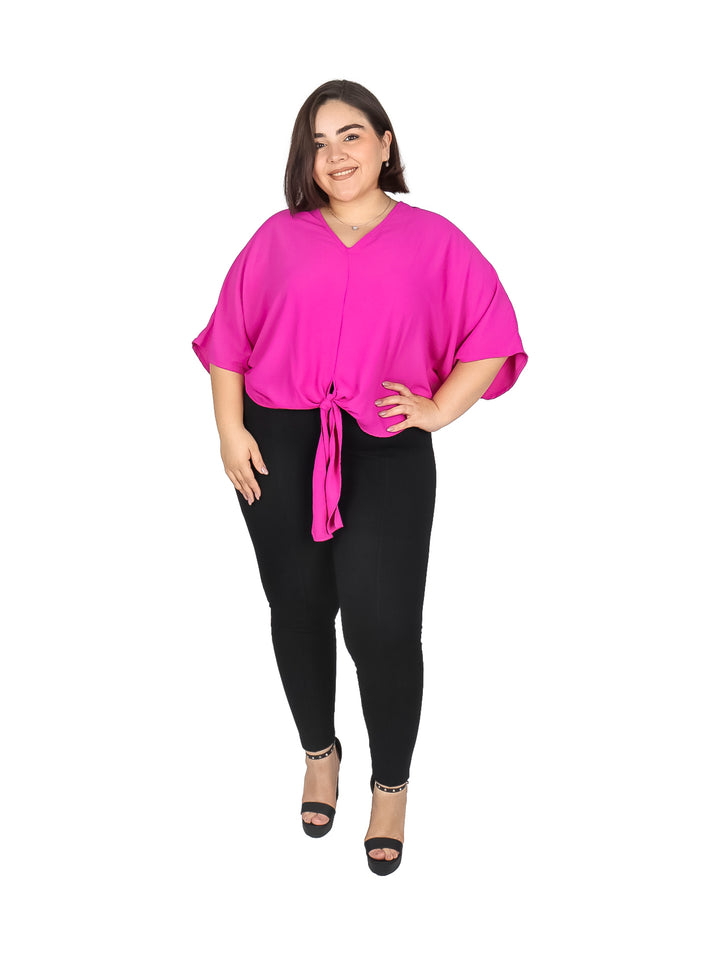 Mujer vistiendo una blusa color rosa intenso con cuello en V y detalle de nudo en la cintura.
