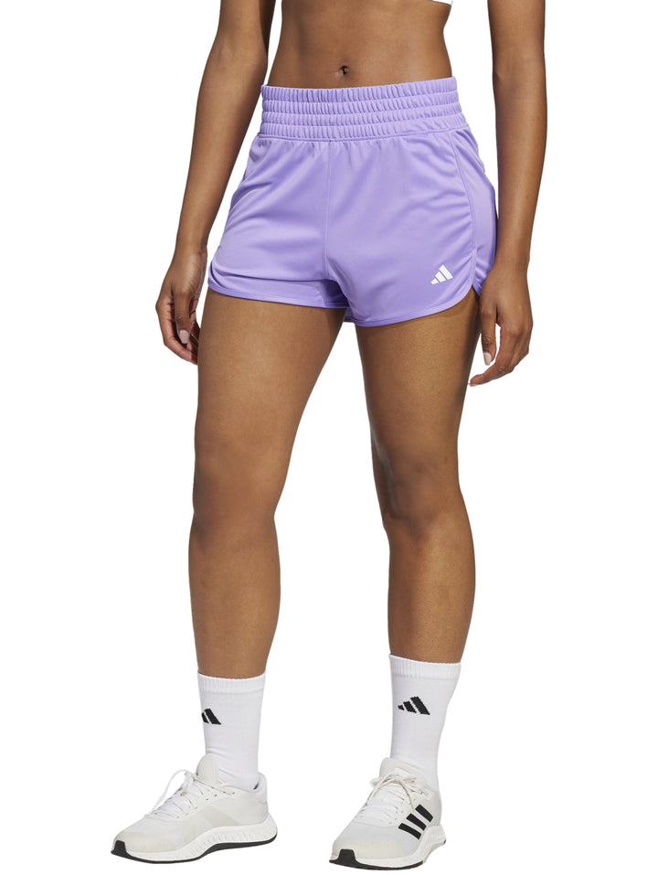 Mujer vistiendo shorts deportivos Adidas de color morado con logotipo blanco