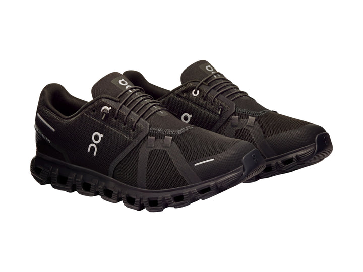 Tenis deportivos On Cloud color negro total con suela característica de nubes y tejido transpirable.