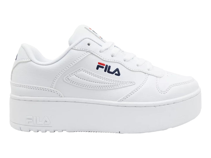 Tenis Fila blancos de plataforma con logotipo en azul y rojo sobre fondo blanco.