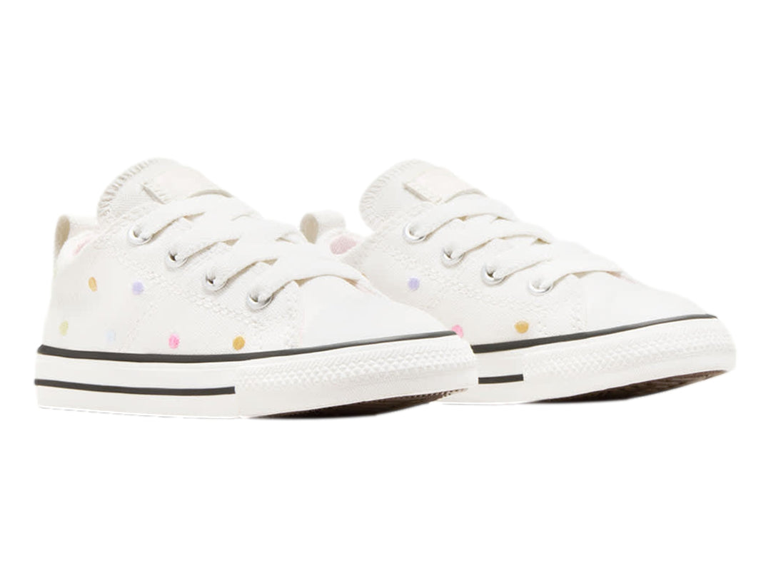Tenis Converse blancos de lona con lunares de colores y suela blanca.