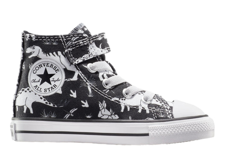 Tenis Converse Chuck Taylor All Star negros con estampado de dinosaurios blancos, punta blanca y cierre de velcro.