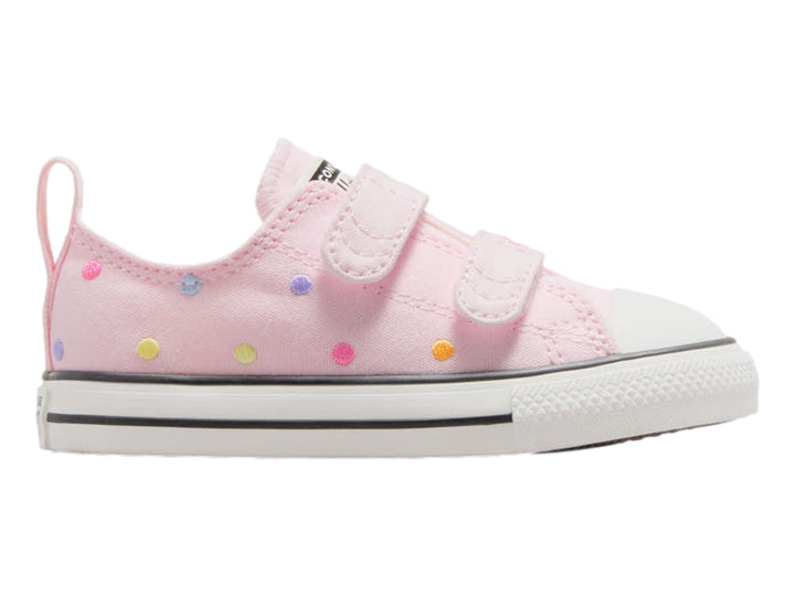 Tenis Converse rosa con lunares multicolores, cierre de velcro y suela blanca.