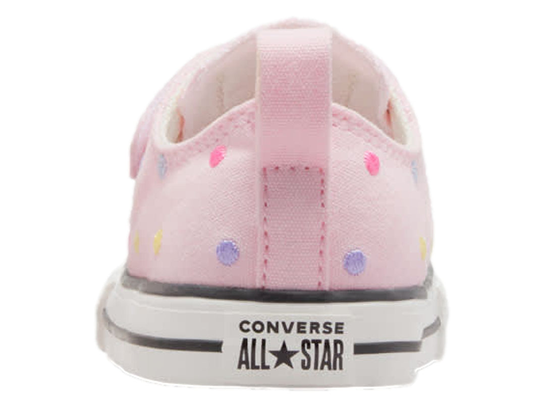 Tenis Converse rosa con lunares multicolores, cierre de velcro y suela blanca.