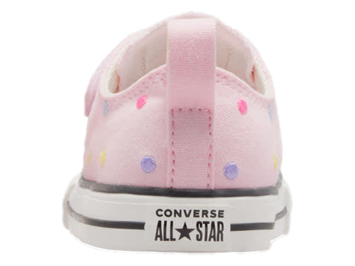 Tenis Converse rosa con lunares multicolores, cierre de velcro y suela blanca.