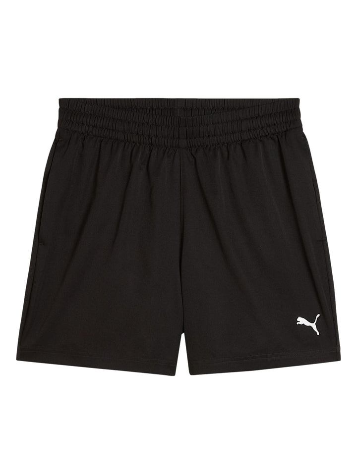 Hombre vistiendo shorts deportivos PUMA de color negro, calcetines blancos y tenis blancos.