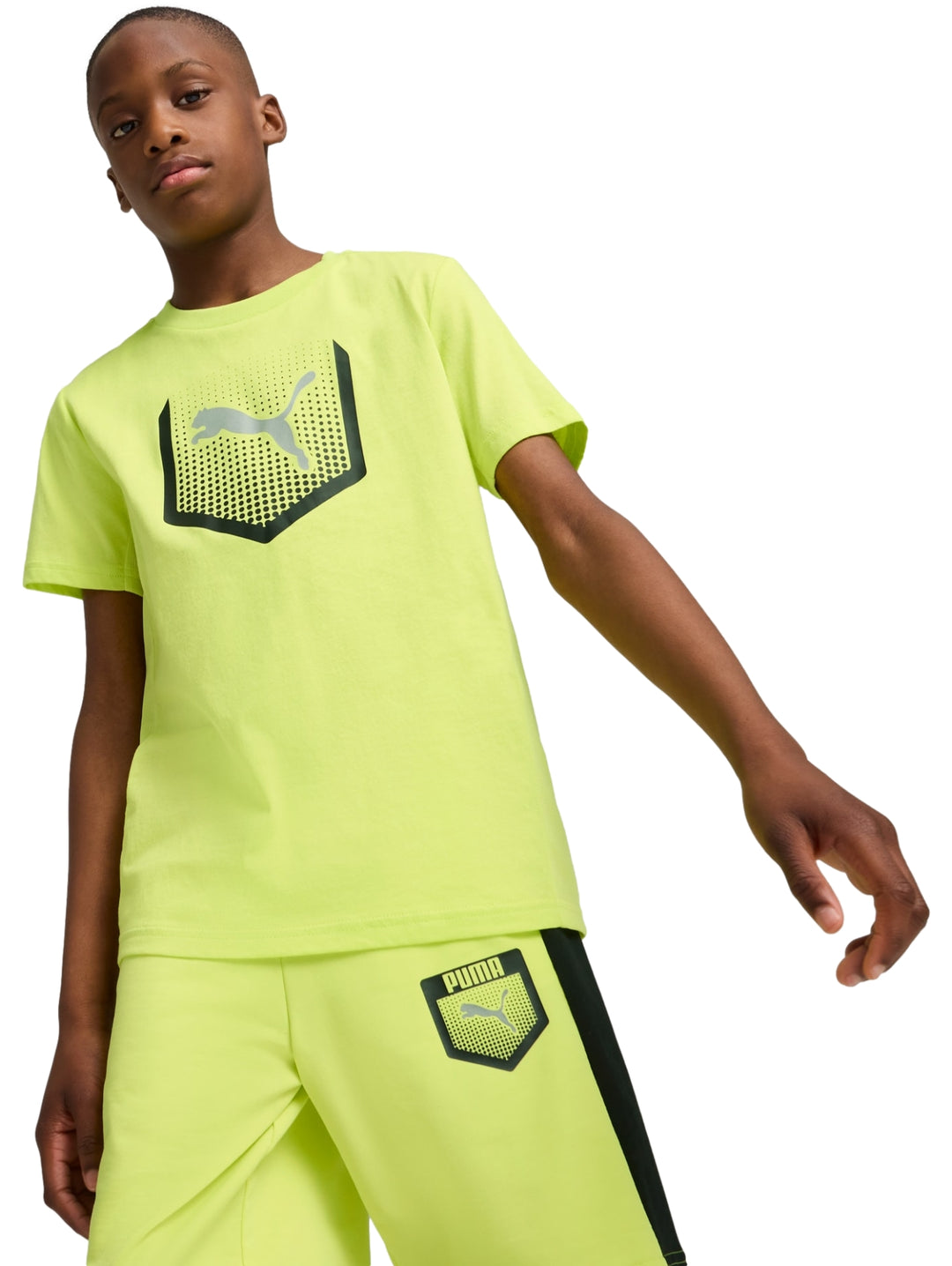 Niño vistiendo camiseta y shorts deportivos color amarillo limón con detalles gráficos en negro de PUMA.