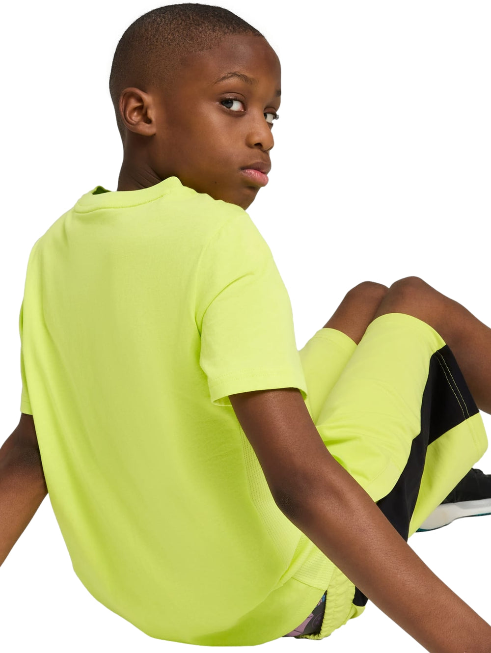 Niño vistiendo camiseta y shorts deportivos color amarillo limón con detalles gráficos en negro de PUMA.