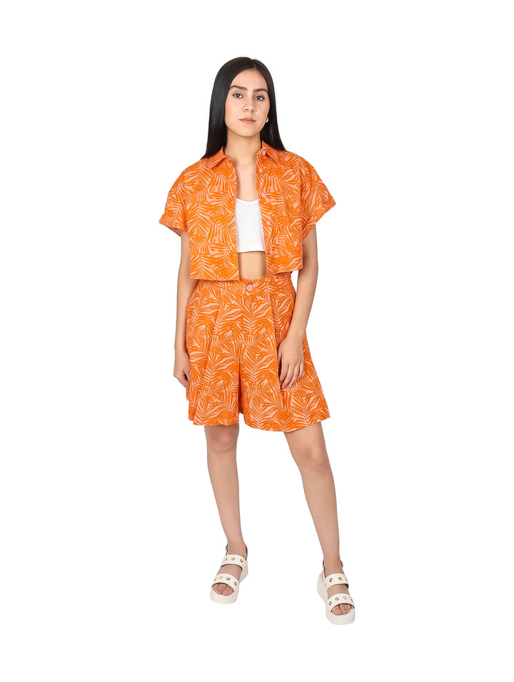 Mujer vistiendo un top corto color naranja con estampado de hojas y botones frontales.