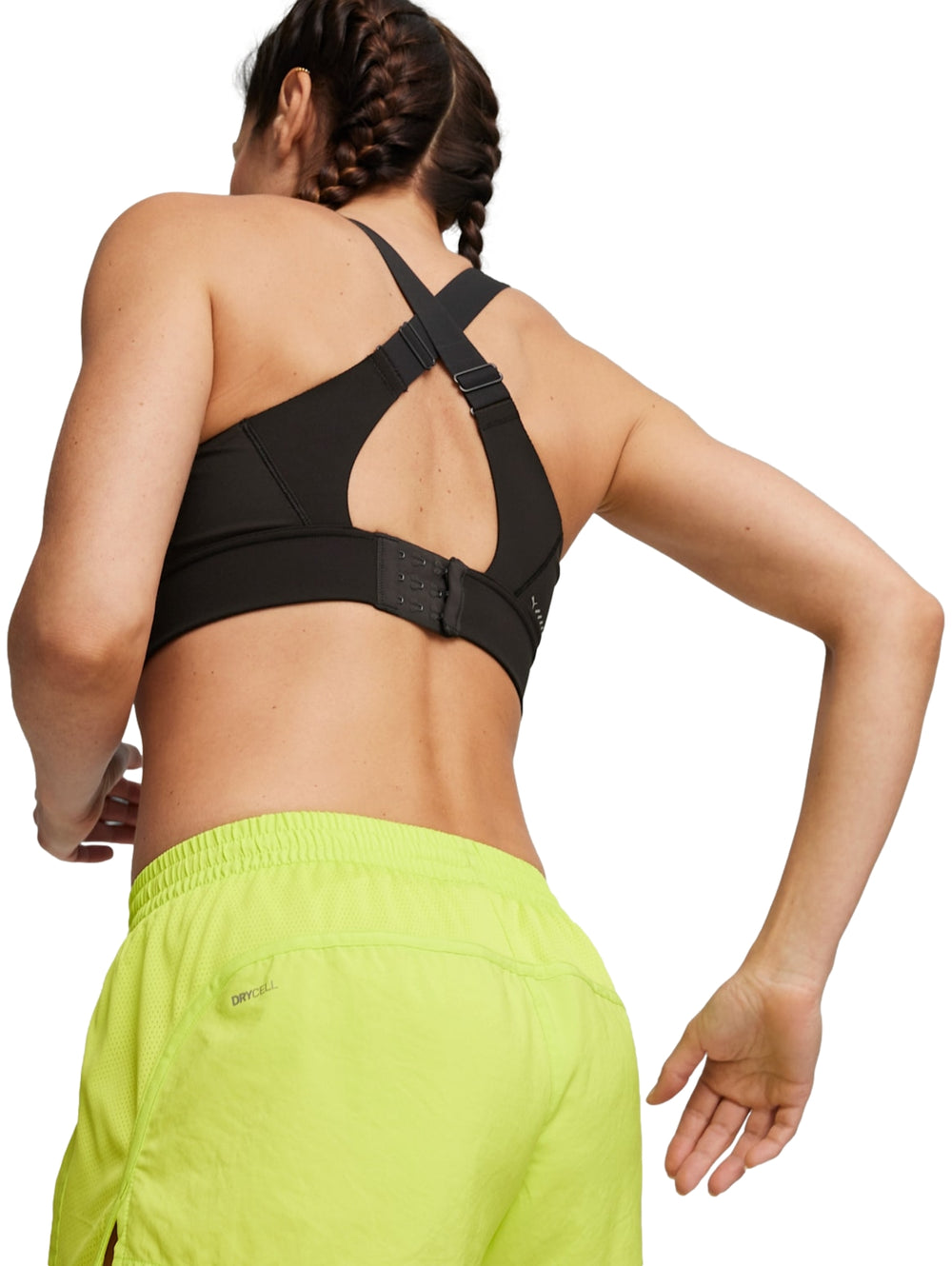 Mujer modelando un bra deportivo PUMA color negro y shorts color amarillo neón.