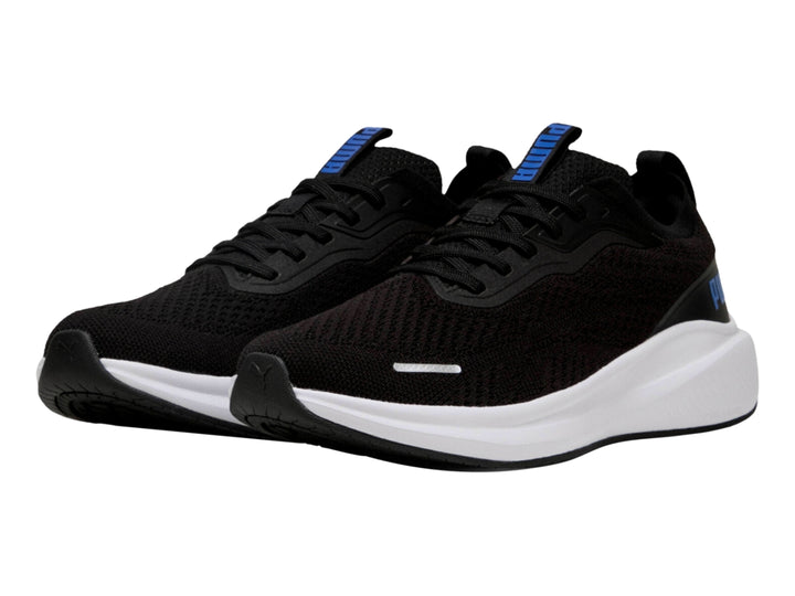 Tenis deportivos PUMA color negro con suela blanca y logo azul en el costado.
