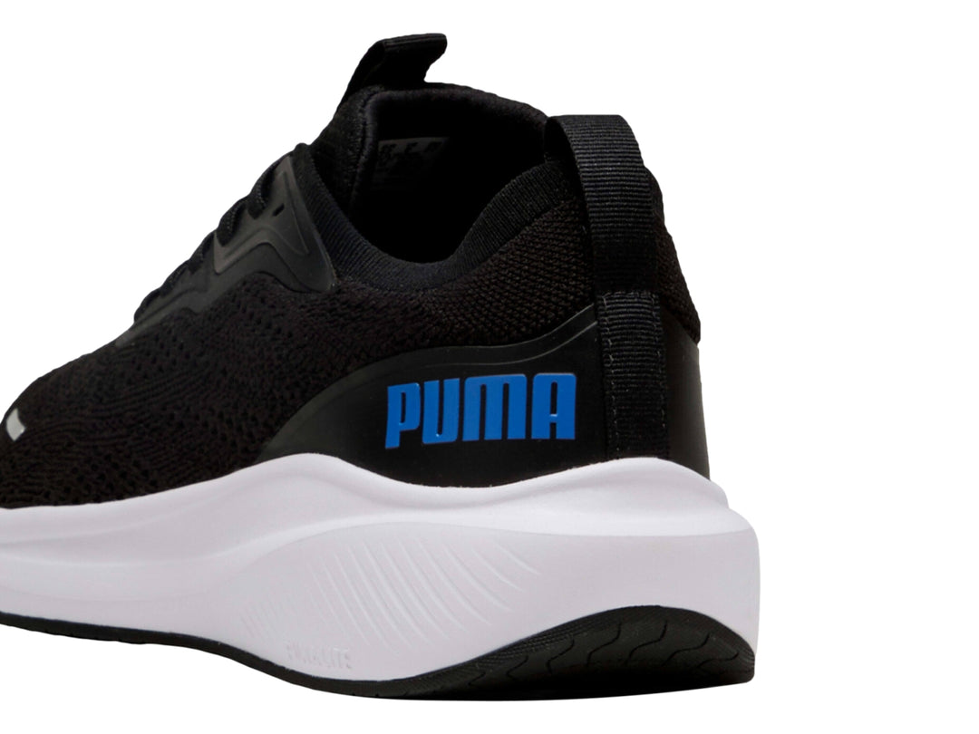 Tenis deportivos PUMA color negro con suela blanca y logo azul en el costado.