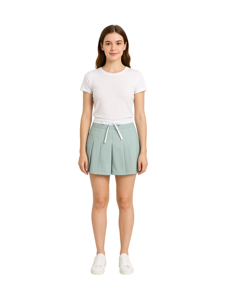 Mujer vistiendo una falda corta de color menta con tablones y cintura ajustable.