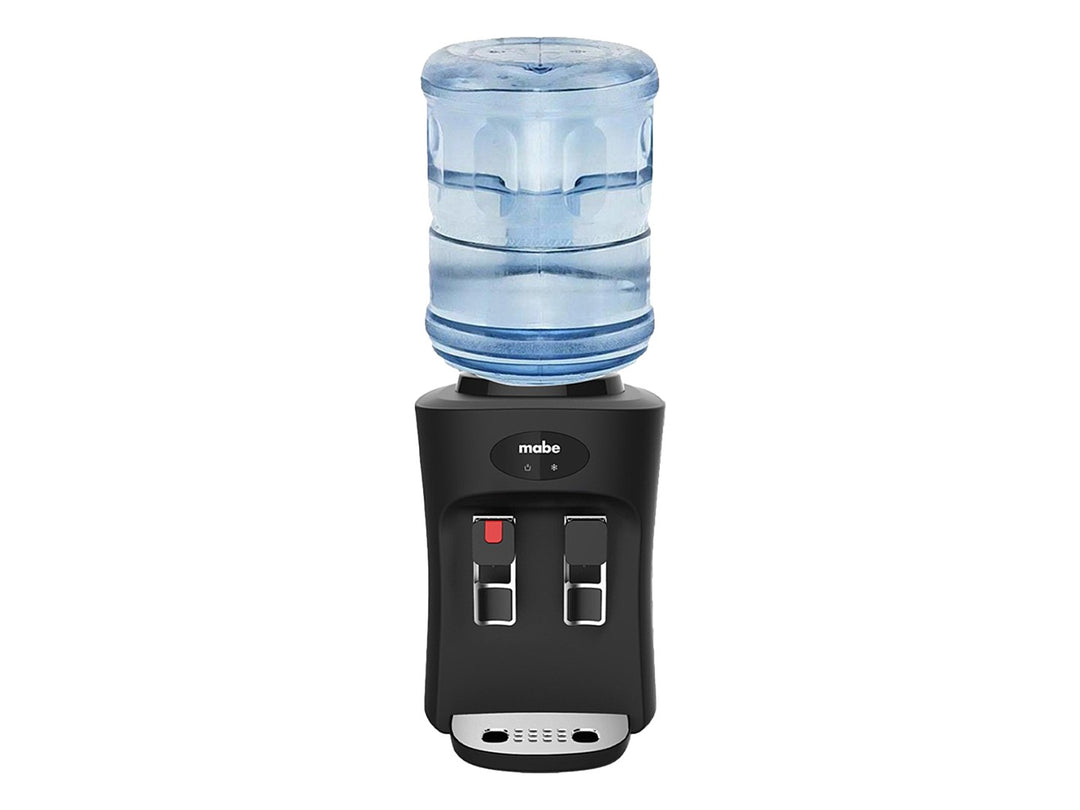 Enfriador de agua sobre mesa Mabe color negro con dos grifos y bandeja de goteo metálica.