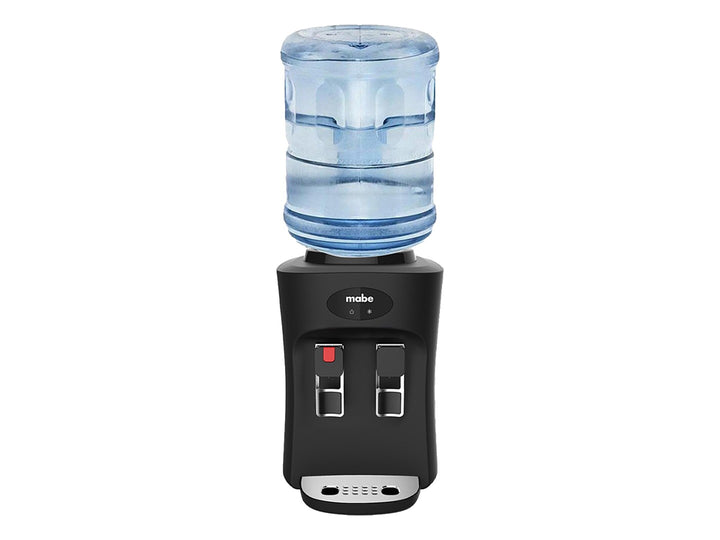 Enfriador de agua sobre mesa Mabe color negro con dos grifos y bandeja de goteo metálica.