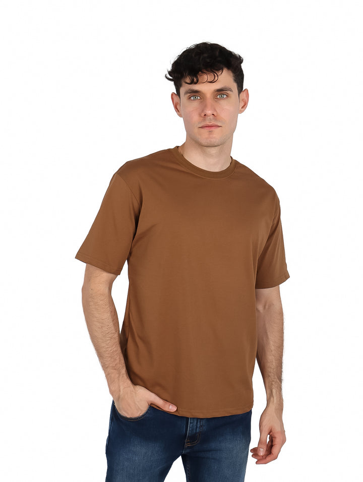 Hombre vistiendo una playera oversize de color café con cuello redondo y manga corta.