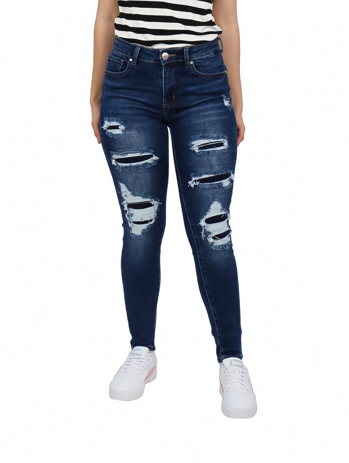 Jeans skinny color azul oscuro con efecto desgastado y roturas decorativas en las piernas.
