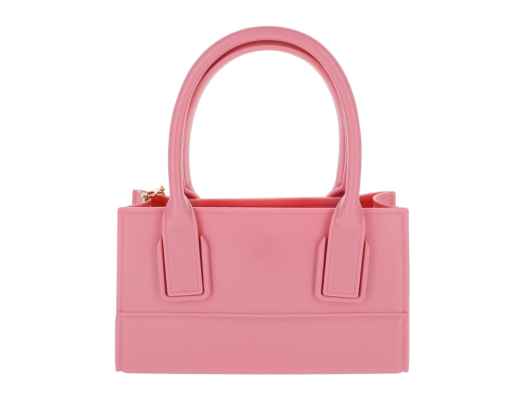 Bolso de mano color rosa pastel con diseño rectangular y asas cortas sobre fondo blanco.