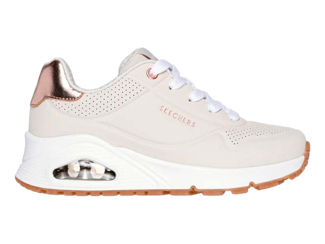 Tenis Skechers color beige con detalles metálicos en oro rosa y suela blanca.