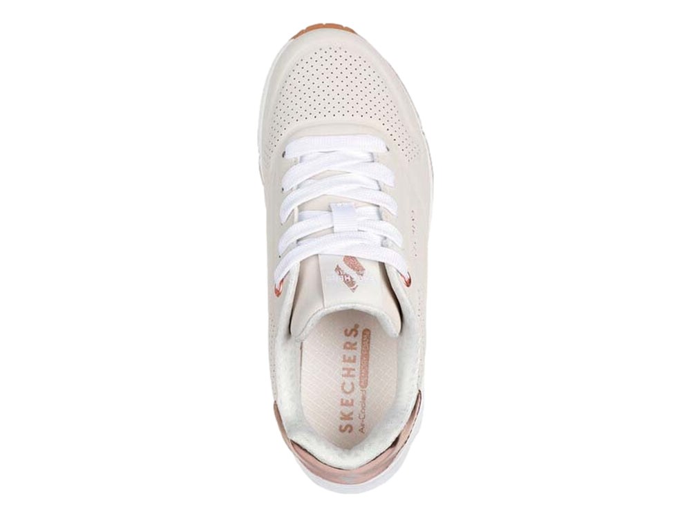Tenis Skechers color beige con detalles metálicos en oro rosa y suela blanca.