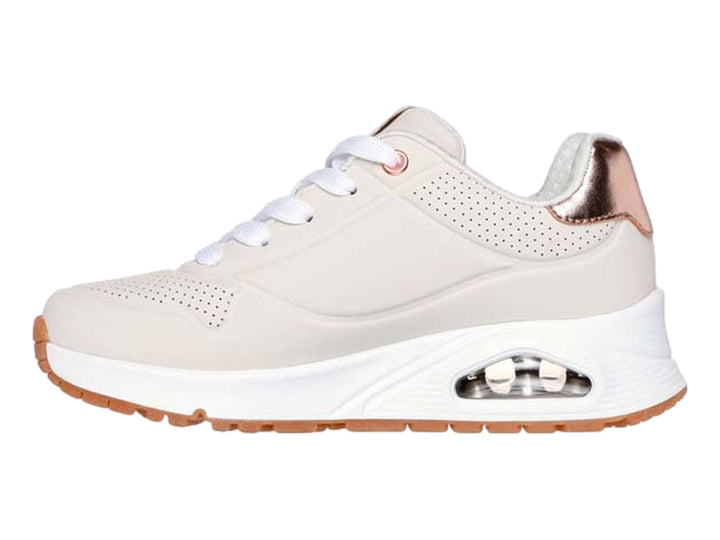 Tenis Skechers color beige con detalles metálicos en oro rosa y suela blanca.