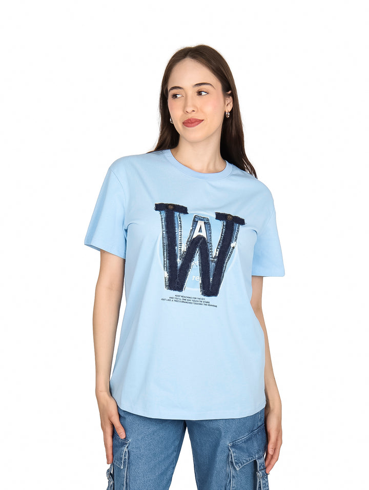 Mujer vistiendo playera azul cielo con estampado de letra W en el pecho.