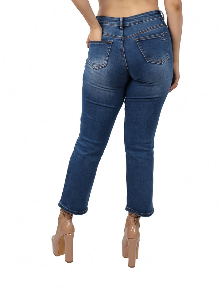 Jeans azul oscuro para mujer con efecto desgastado y roturas en las piernas.