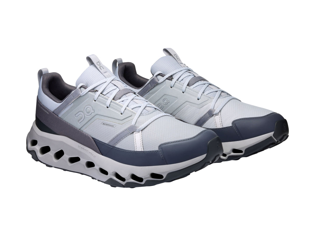 Tenis deportivos On Cloud en colores blanco, gris y azul marino con suela tecnológica perforada.