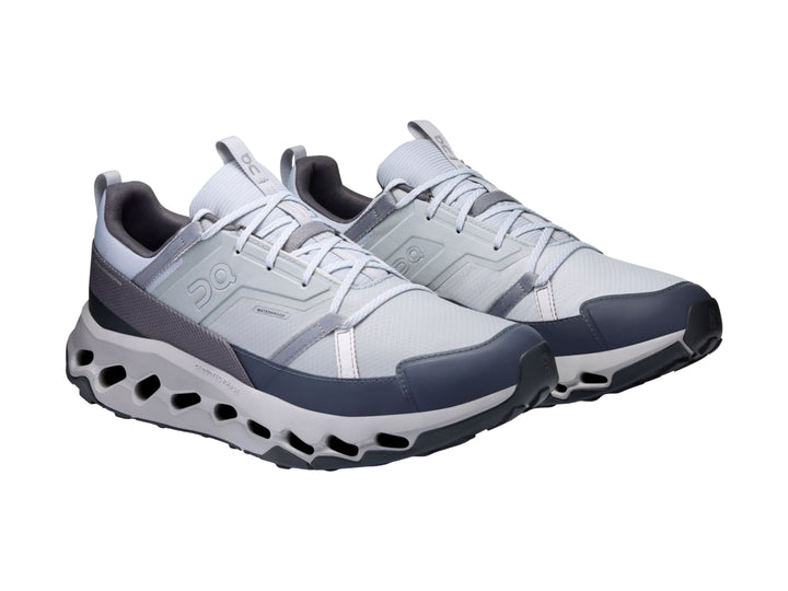 Tenis deportivos On Cloud en colores blanco, gris y azul marino con suela tecnológica perforada.
