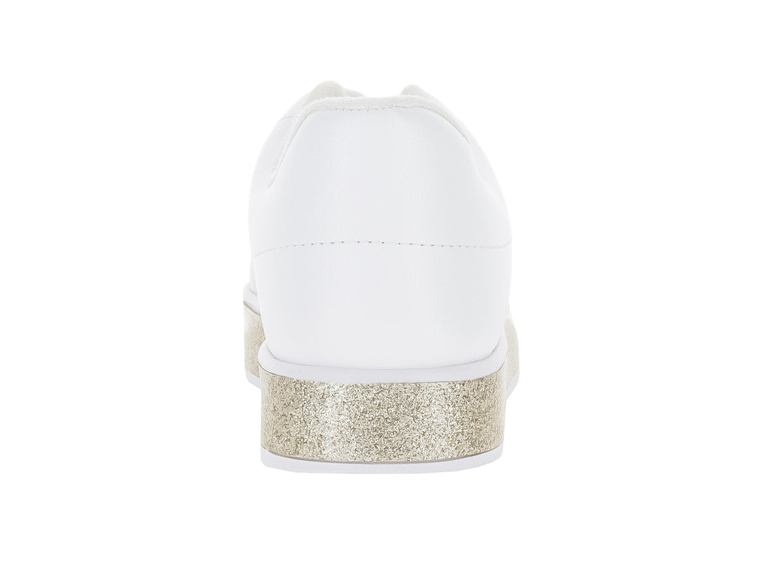 Tenis blancos para niña con suela gruesa en color dorado brillante y agujetas blancas.