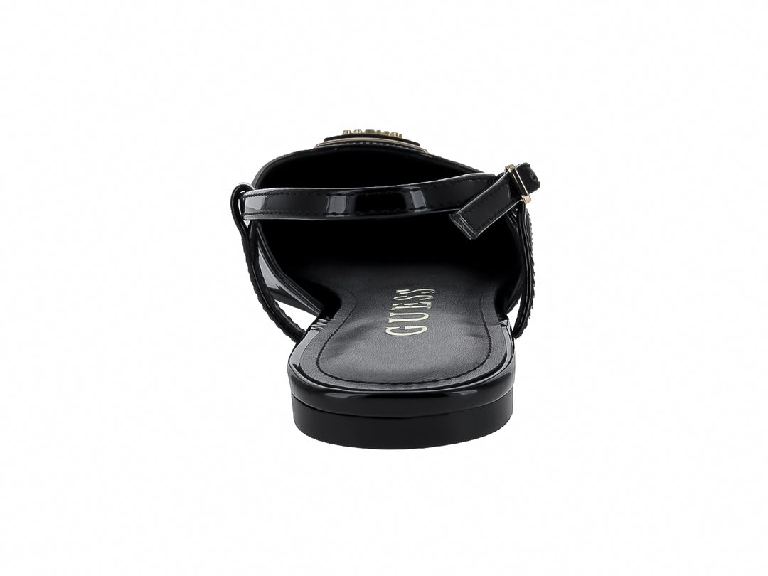 Zapato plano negro brillante de punta afilada con correas y adorno dorado frontal.