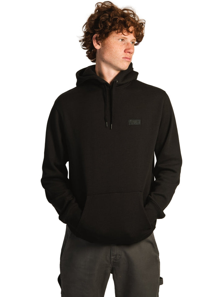 Hombre vistiendo una sudadera con capucha color negro de la marca Vans con bolsillo frontal.