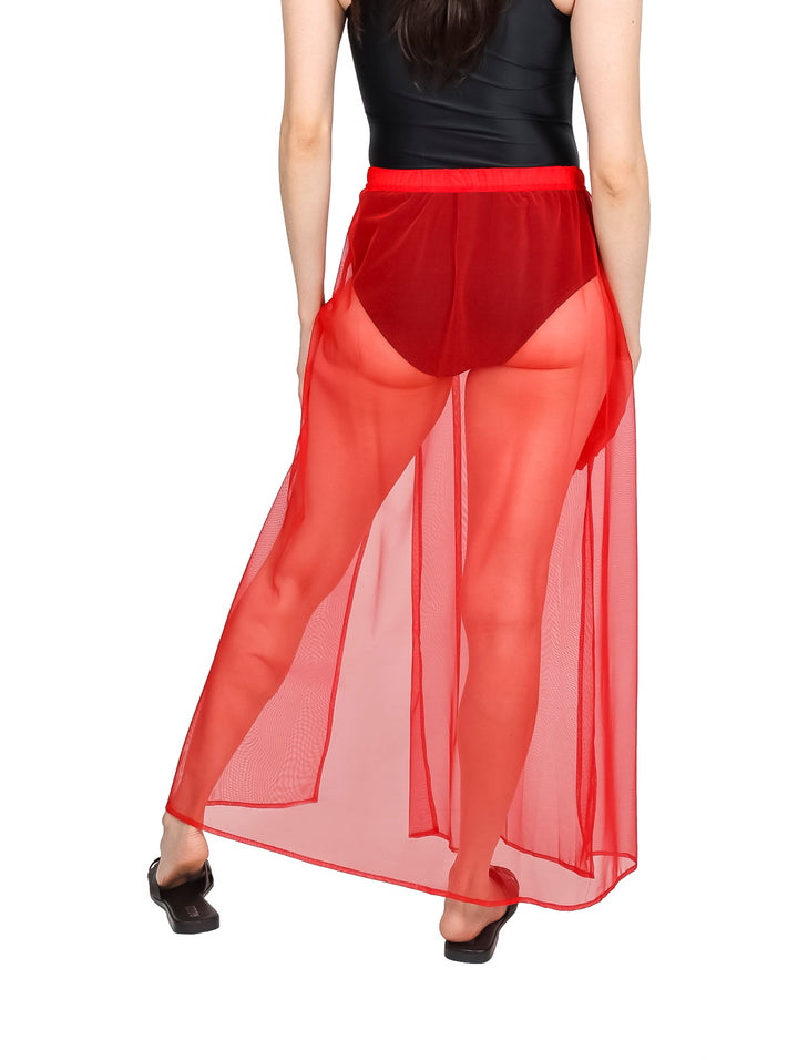 Falda larga de malla color rojo para playa sobre traje de baño negro.