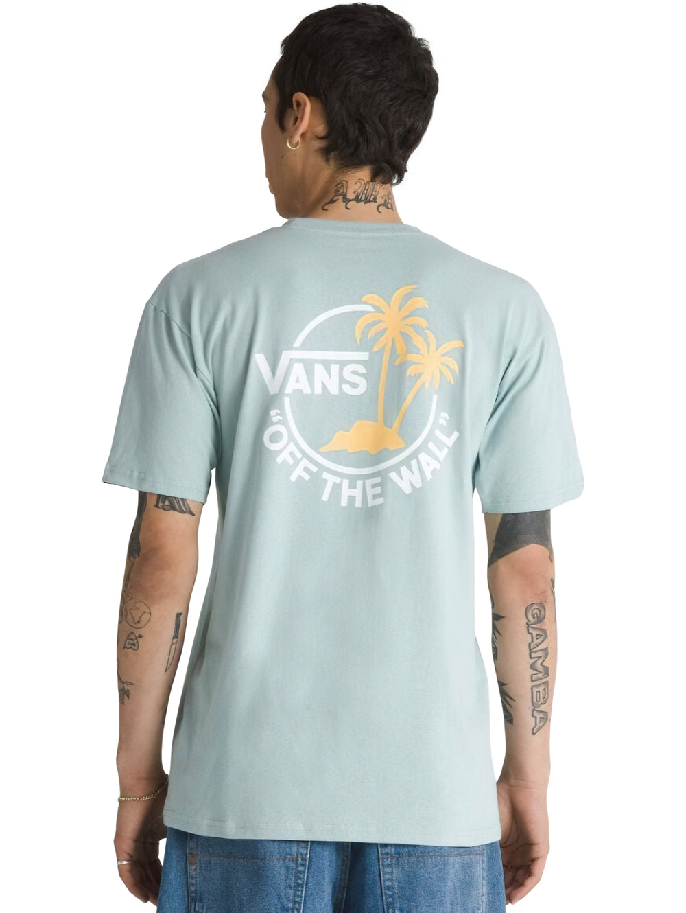 Hombre vistiendo playera Vans de color gris claro con un pequeño logotipo en el pecho.