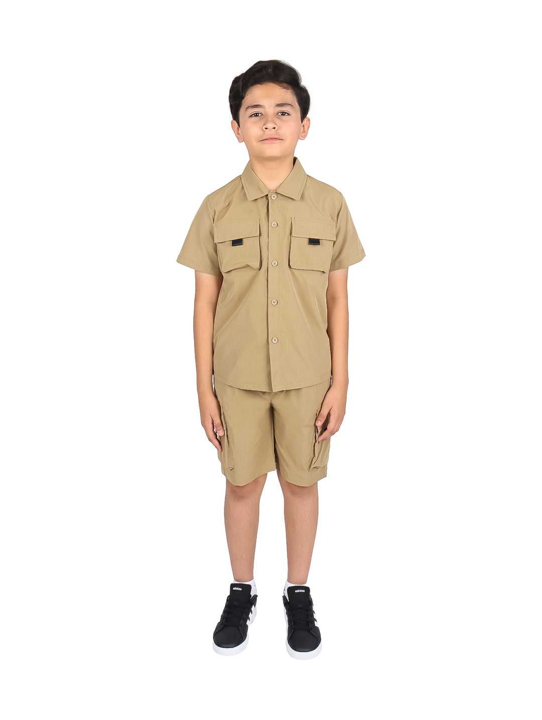 Niño vistiendo un conjunto casual de camisa y shorts en color khaki con tenis negros.