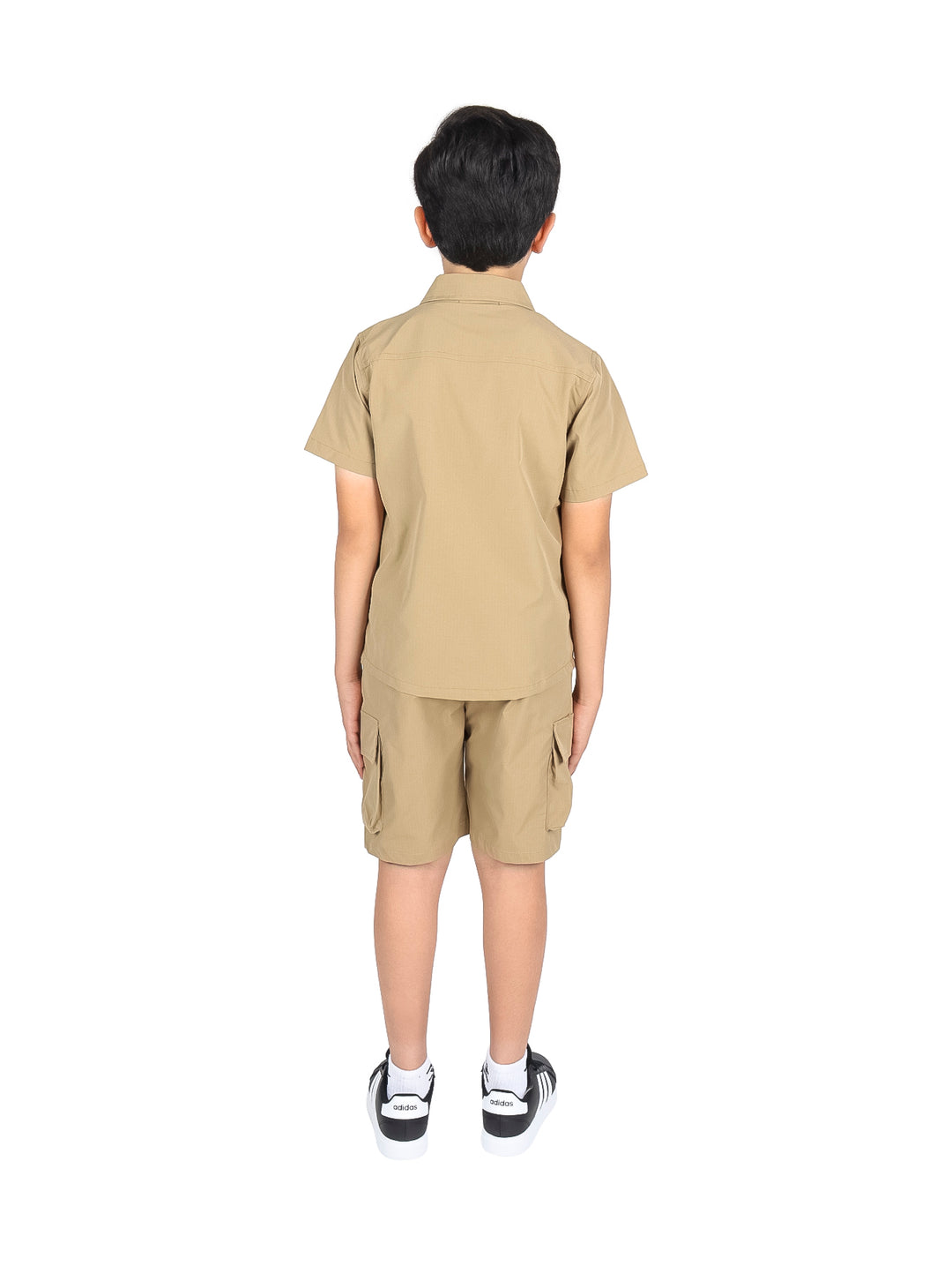 Niño vistiendo un conjunto casual de camisa y shorts en color khaki con tenis negros.