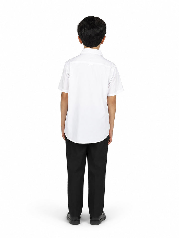 Niño con camisa blanca de manga corta y pantalones negros sobre fondo blanco.