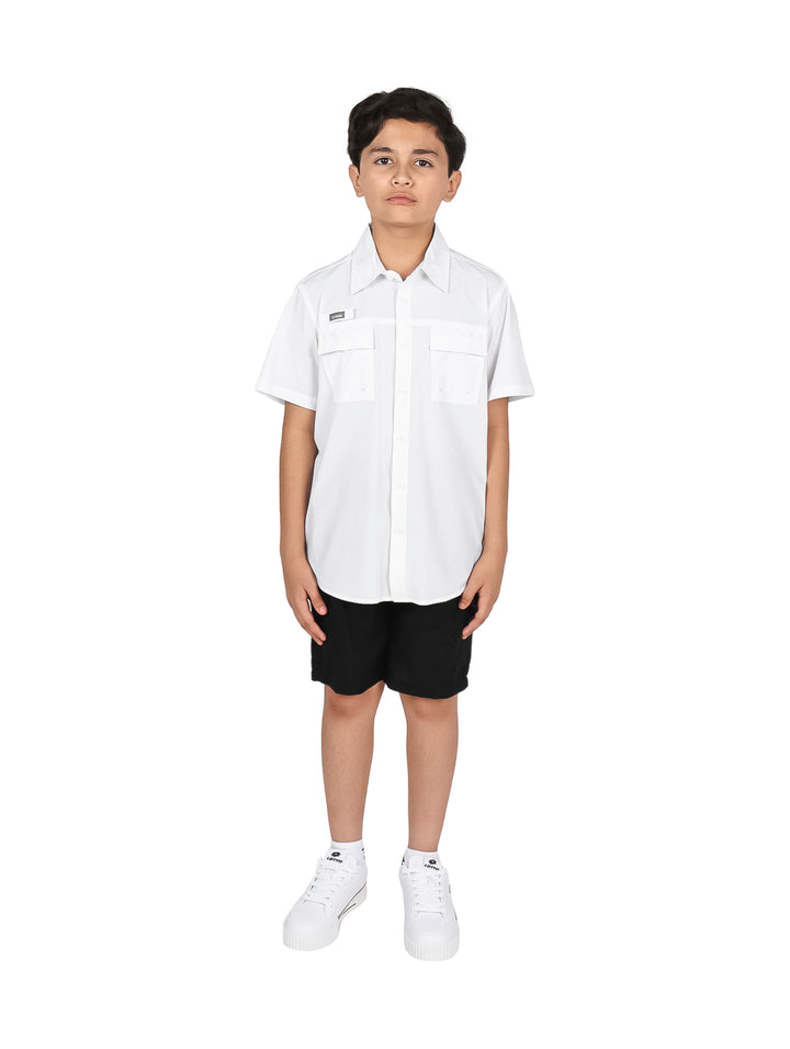 Niño con camisa blanca de manga corta y pantalones negros sobre fondo blanco.