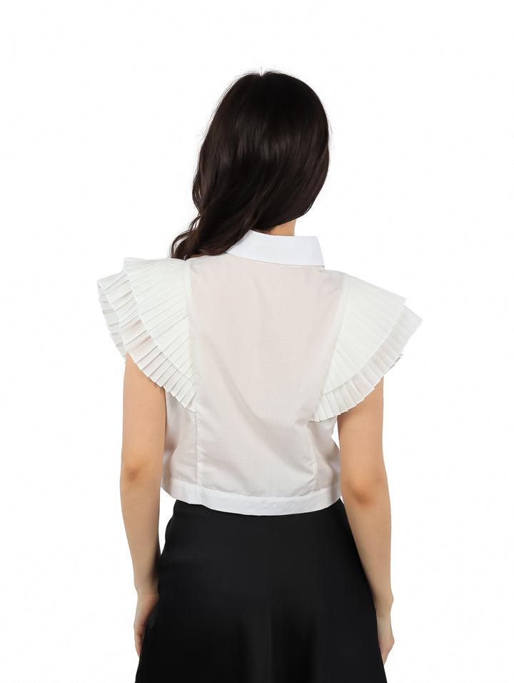 Blusa blanca de popelina sin mangas con cuello y detalles de volantes frontales y laterales.
