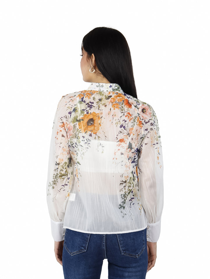 Blusa blanca de manga larga con estampado floral en tonos naranja y verde, con cuello y botones frontales.