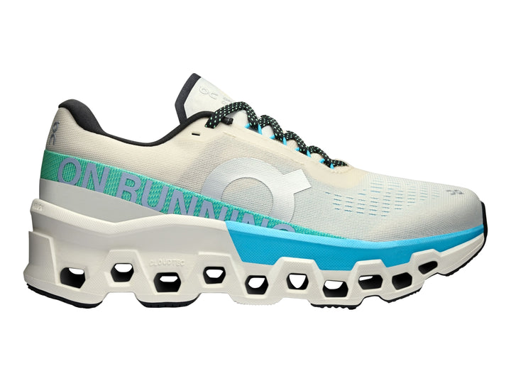 Tenis deportivos On Cloudmonster 2 en color crema con detalles en azul y suela blanca estructural.