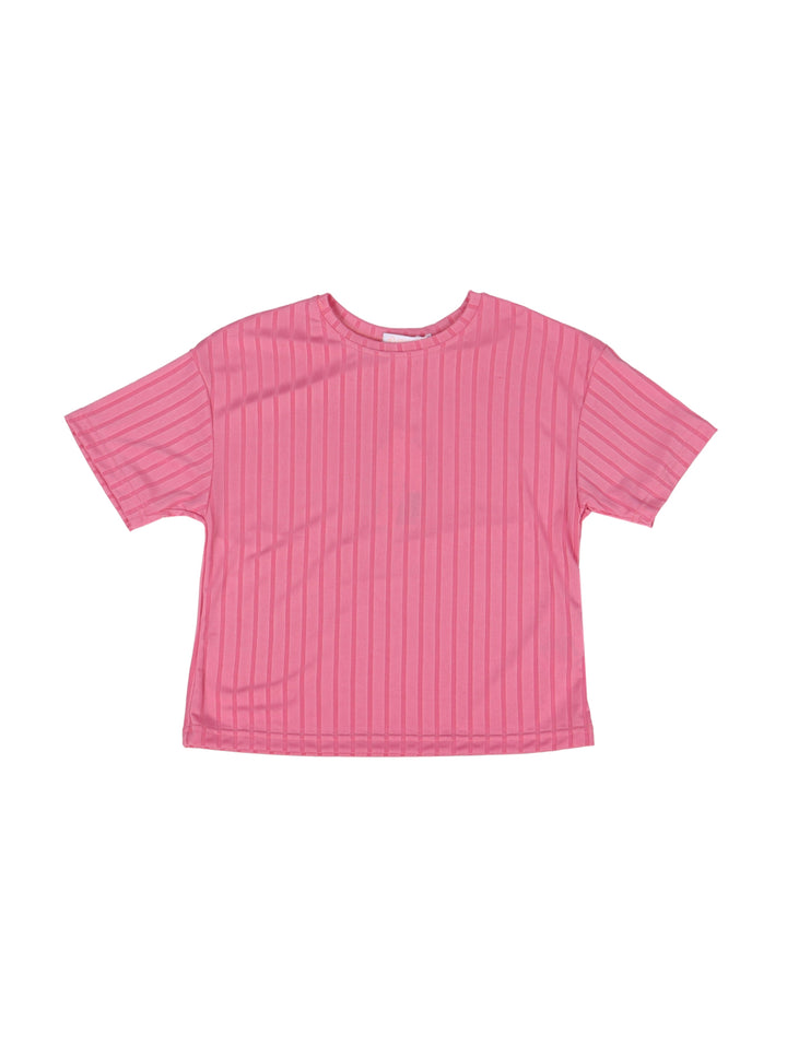 Niña vistiendo un conjunto de camiseta y pantalón acanalado en color fucsia con tenis blancos.