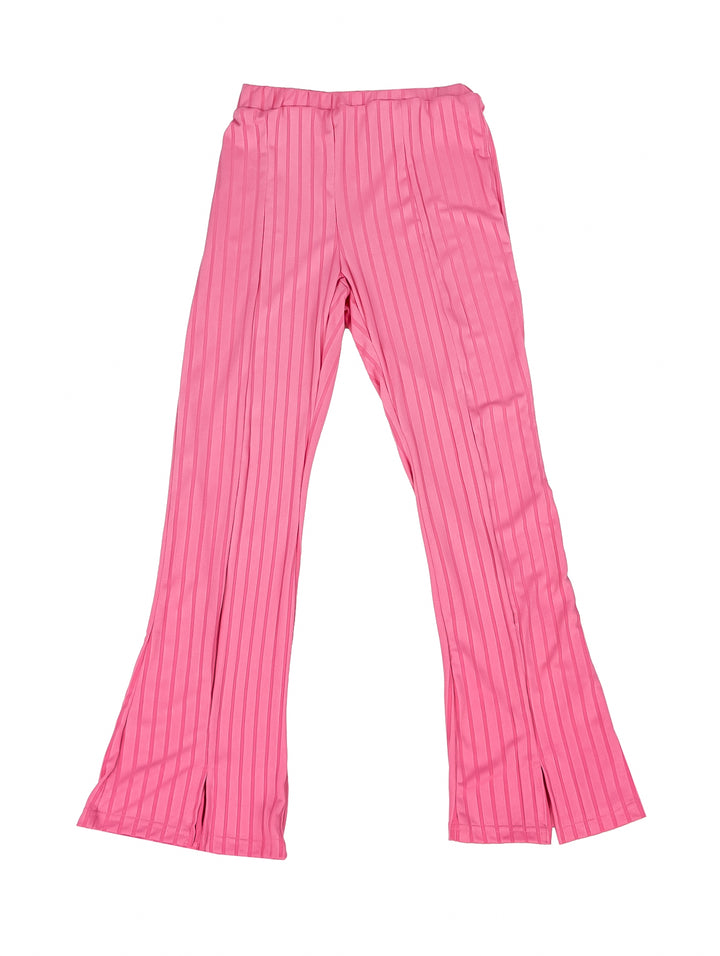 Niña vistiendo un conjunto de camiseta y pantalón acanalado en color fucsia con tenis blancos.