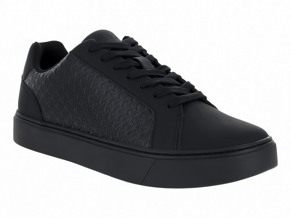 Tenis negros de cuero con textura geométrica en los laterales y suela plana.