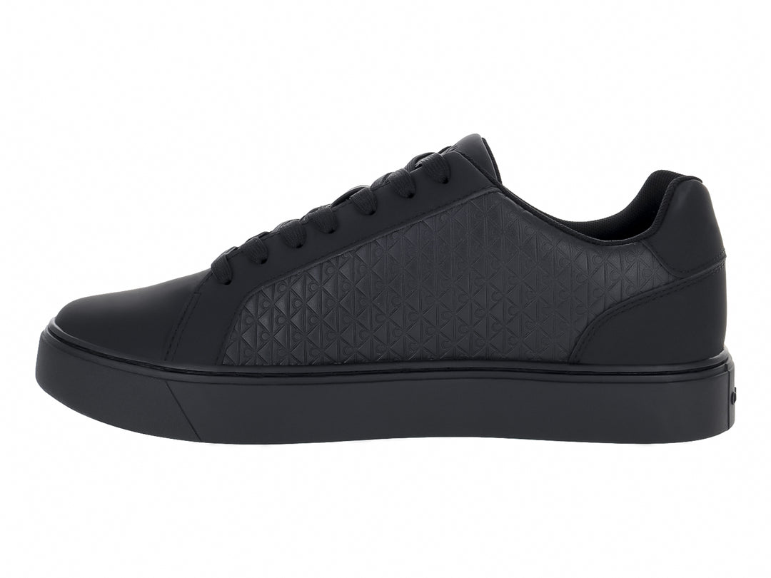 Tenis negros de cuero con textura geométrica en los laterales y suela plana.