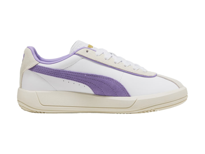 Tenis PUMA blancos con detalle lateral en color lavanda y suela en tono blanco cálido.
