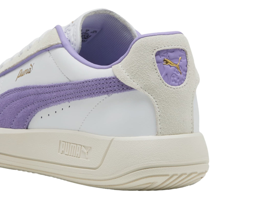 Tenis PUMA blancos con detalle lateral en color lavanda y suela en tono blanco cálido.